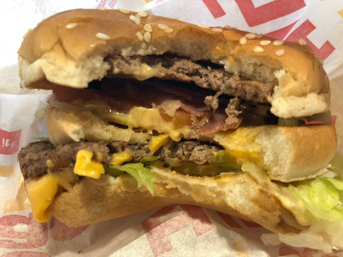 Open BIG MAC BLT burger with visible layers of beef, cheese, lettuce, and bacon.